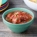 A table with bowls of salsa and chips, one of the bowls is rainforest green with a diamond pattern.