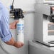 A man holding a Bunn water filtration cartridge in a professional kitchen.