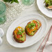 A plate of two small sandwiches on an Acopa Condesa porcelain platter on a table.