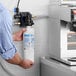 A man holding a Bunn water filter in a white plastic container in a professional kitchen.