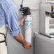 A man holding a Bunn water filtration cartridge in front of a sink.