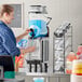 A woman using a Narvon slushy dispenser to pour a drink.