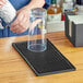 A clear glass on a Franmara black rubber bar mat.