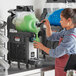 A woman pouring green slushy mix into a Carnival King granita machine.