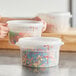 A woman using a white Choice translucent plastic container to hold colorful candies.