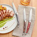 A plate of meat and potatoes with an Acopa steak knife on a napkin.