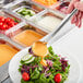 a spoon pouring a dressing over a salad