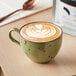 A mug of Arrosto Costa Rica whole bean coffee with latte art on top on a table.