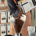 A person pouring Arrosto Costa Rica whole bean coffee into a glass container.