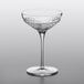 A Luigi Bormioli Roma coupe wine glass with a clear liquid, on a gray surface.