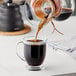 A person pouring Arrosto Guatemala Chiquimula coffee into a glass cup.