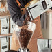 A man pouring Arrosto Guatemala Chiquimula coffee beans into a grinder.