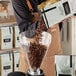 A person pouring Arrosto Sumatra Mandheling whole bean coffee into a glass container.