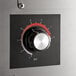 A close-up of a dial with numbers and a red circle on a metal box.