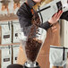 A woman pouring Arrosto Kenya AA whole bean coffee into a grinder.