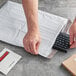 A person opening a white Lavex Self-Sealing Polyethylene Bubble Mailer with a keyboard.