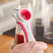 A hand holding a Franmara pink multi-purpose bottle opener.
