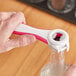 A person using a Franmara pink multi-purpose bottle opener to open a bottle on a counter.