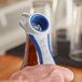 A person's hand using a Franmara blue multi-purpose opener with a corkscrew and bottle opener.