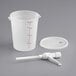 A white plastic container with a spout and a white plastic measuring cup with red lines.