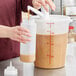 A person using a Choice condiment pump to pour brown liquid into a plastic container.