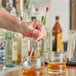 A person using a Choice bar spoon with a red knob to stir two glasses of liquid.