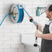 A man using a Regency stainless steel hose to clean a wall.