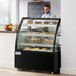 An Avantco dry bakery display case with pastries on trays.