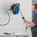 A man using a Regency powder-coated steel hose reel to clean a wall.