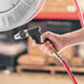 A hand holding a black and silver Regency 5 GPM spray water gun for a hose.