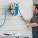 A man using a Regency stainless steel hose reel to clean a wall.