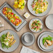 A table with Acopa Apollo matte grey and black melamine bowls full of food.