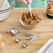 A person using Choice stainless steel measuring spoons to measure brown sugar in a glass bowl.