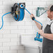 A man using a Regency hose reel and water gun to clean a wall.