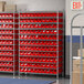 A Regency wire shelving unit with red bins on the shelves.