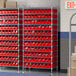A Regency wire shelving unit with red bins on shelves.