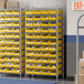 A white metal Regency wire shelving unit with yellow storage bins.