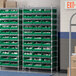 A white wire shelving unit with green bins on the shelves.