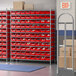 A Regency wire shelving unit with red bins on shelves in a warehouse.