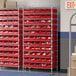 A Regency wire shelving unit with red bins on metal shelves.