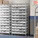 A Regency metal wire shelving unit with clear plastic bins on it.