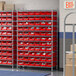 A Regency wire shelving unit with red storage bins on each shelf.