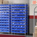 A Regency wire shelving unit with blue shelves and blue bins.
