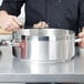 A chef using a Vollrath Centurion brazier pan to cook food on a counter.