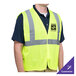 A man wearing a lime high visibility safety vest with reflective stripes.