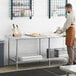 A man in an apron at a Regency stainless steel work table with undershelf.