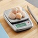 A stainless steel digital portion control scale with raw scallops placed on its weighing platform.