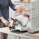 A man using a Berkel medium-duty meat slicer to cut meat.