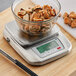 An AvaWeigh stainless steel digital portion scale with a bowl of mussels on it.