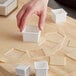 A hand using the Ateco plastic square cutter to cut dough into a square.